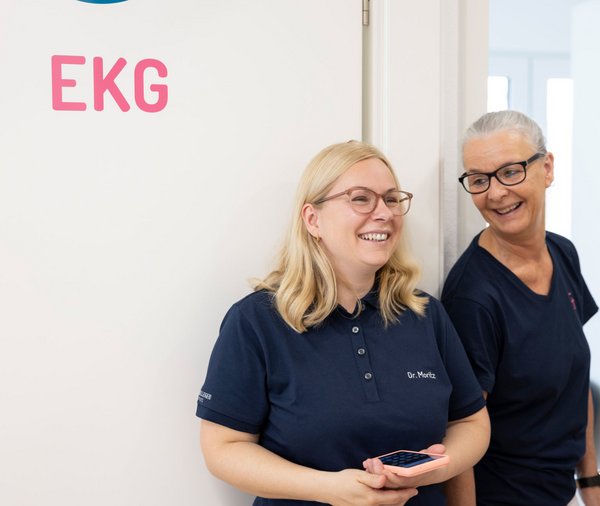 Zwei Frauen stehen vor dem EKG-Raum der Hausarztpraxis Dr. Schön & Kollegen
