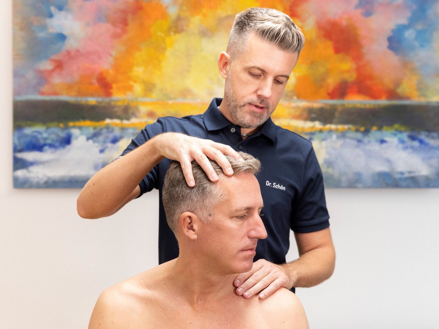 Dr. Schön & Kollegen Manuelle Medizin Dr. Schön untersucht den Nacken eines Patienten